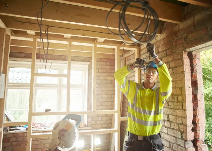  Un homme en gilet de sécurité jaune travaille sur une maison, effectuant des réparations ou des améliorations